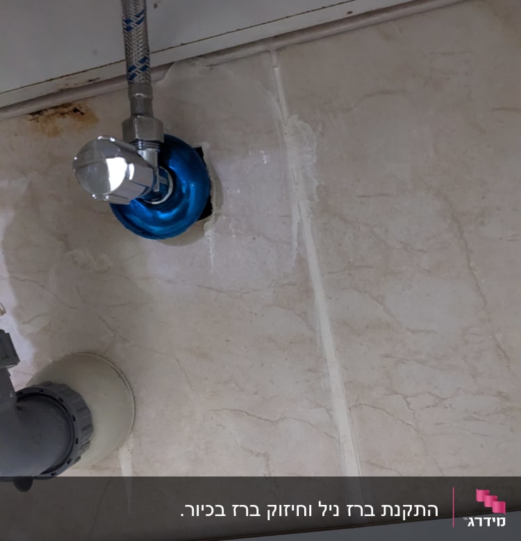 צינור מים עם ברז וכיסוי כחול על קיר